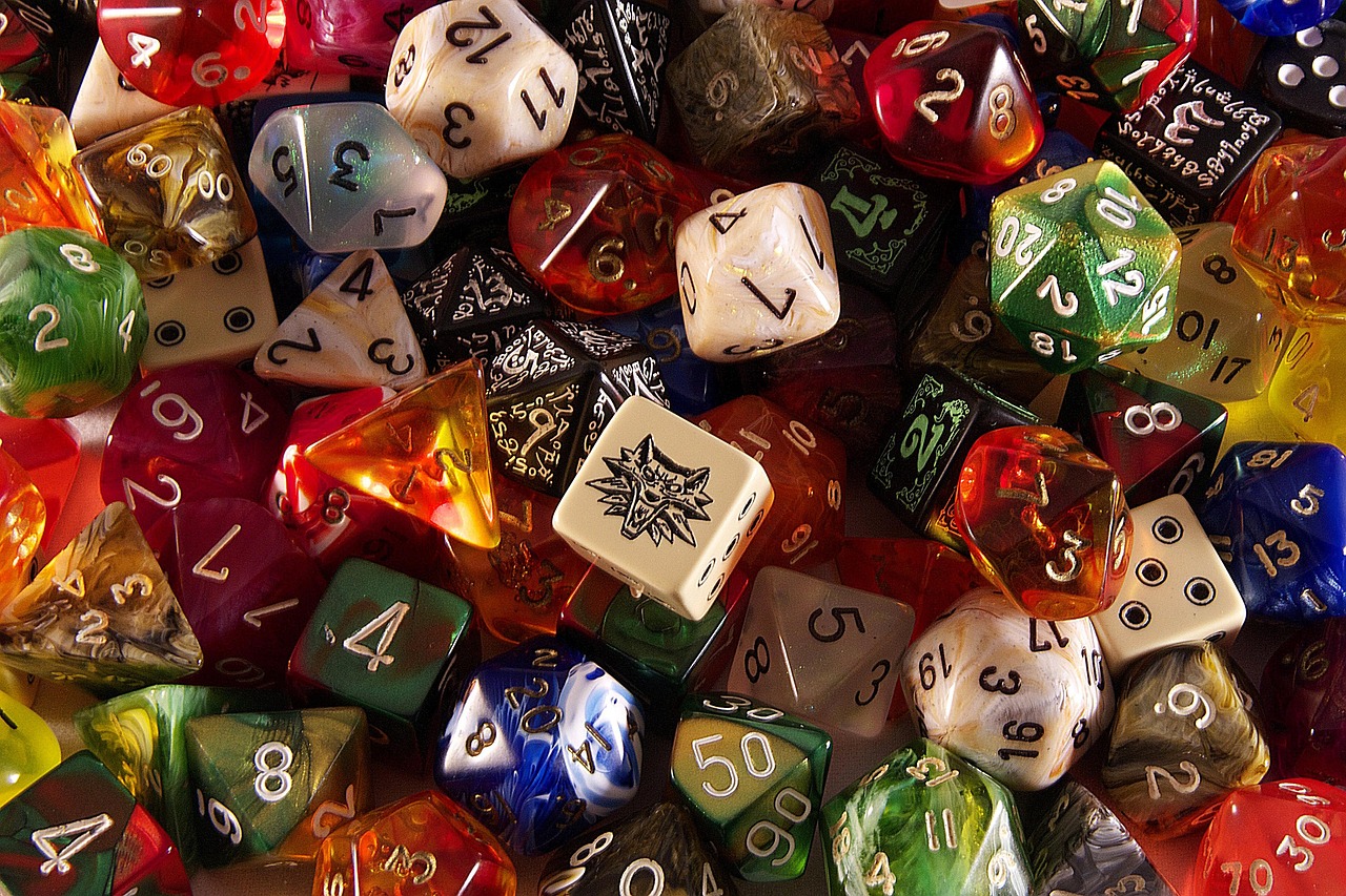 Five dice on a wooden table beside a scorepad